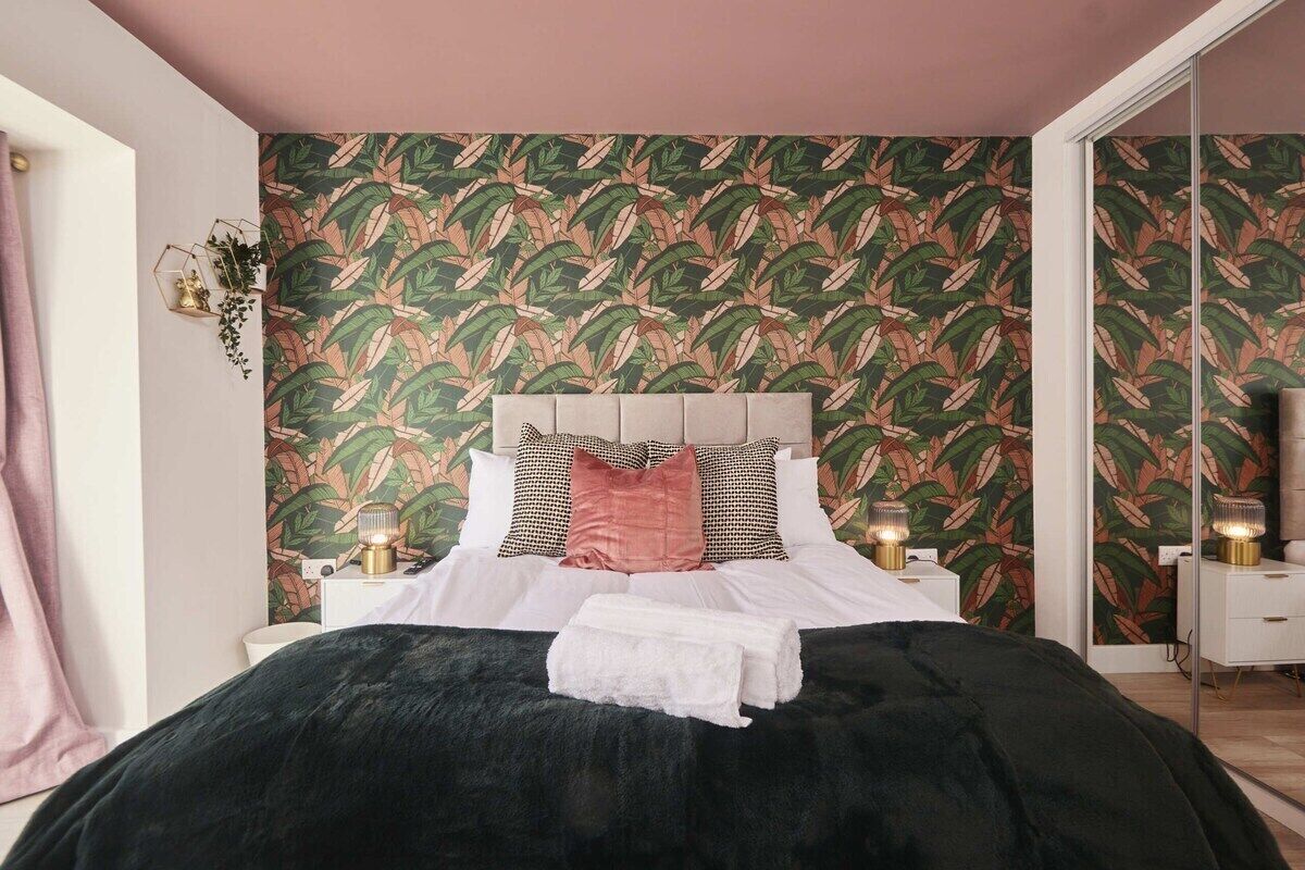 Une chambre à coucher avec un lit, une table de chevet, une lampe et un miroir.