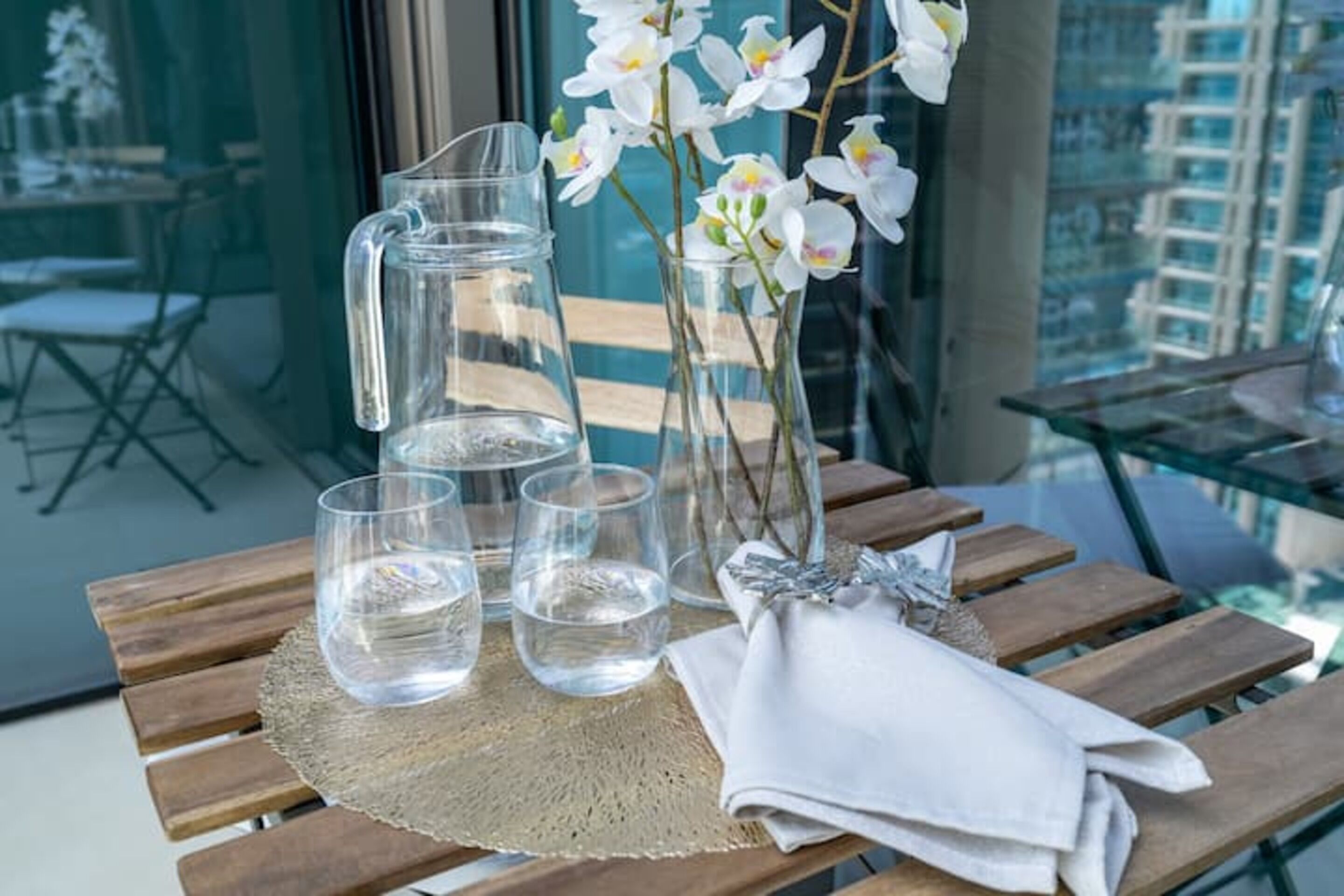Ein Holztisch mit einer Kanne, Gläsern und einem Blumenstrauß.