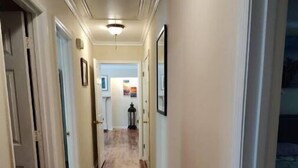 A hallway with wooden flooring, white walls, and framed pictures. - Quiet retreat (Macon)
