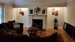 A living room with a fireplace, a ceiling fan, and artwork on the walls. - Quiet retreat (Macon)