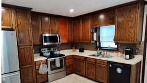 A kitchen with wooden cabinets, stainless steel appliances, and a tiled floor. - Quiet retreat (Macon)