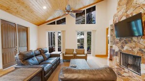 A spacious living room with a high ceiling, leather sofas, a coffee table, and a stone fireplace. - 2 Home Sport Complex W/ Private Lake & Theater! (Jensen Beach)