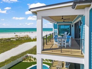 A beachfront property with a balcony overlooking the ocean, a pool, and a patio area with outdoor seating. - Beachfront Luxury - Resort Pool - Steps to Village (Siesta Key)