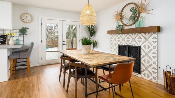 A dining area with a wooden table, chairs, and a hanging light fixture. - 10 Min to Downtown~Luxury Home w/ Pool, Outdoor TV (Austin)