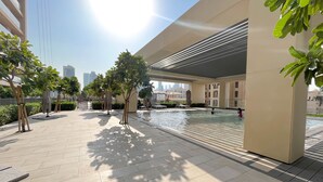 Un espace extérieur moderne doté d’une piscine, de chaises longues et de plantes en pot.