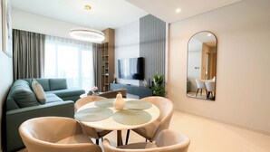 Un salon moderne comprenant un canapé, une table à manger, des chaises, un téléviseur et un grand miroir.