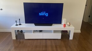 A flat-screen TV on a white entertainment center with a 'sling' logo on the screen. - Visiting family need space? Enjoy our spacious & serene abode. Plenty of space! (Warner Robins)