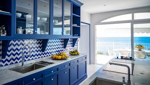 A modern kitchen with blue cabinets and a view of the sea. - Villa Biancalisa - Sea View Infinity Pool - Newly refurbished - Beachfront (Massa Lubrense)