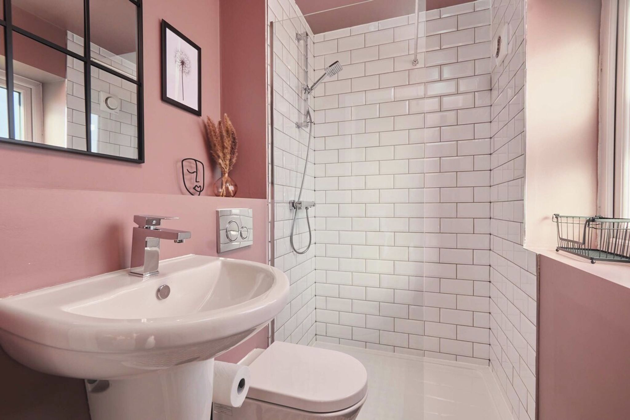 A bathroom with a white sink, toilet, and shower with white tiles.