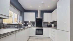 Een moderne keuken met witte kastjes, een roestvrijstalen afzuigkap en een oven.