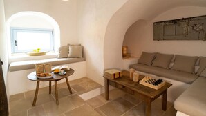 Una sala de estar acogedora con un sofá, una mesita con un tablero de ajedrez, una ventana con vistas y un banco con cojines.