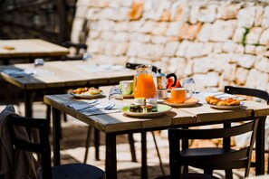 A wooden table set with plates of food, a pitcher of orange juice, and various condiments. - Masseria Soluco (Monopoli)