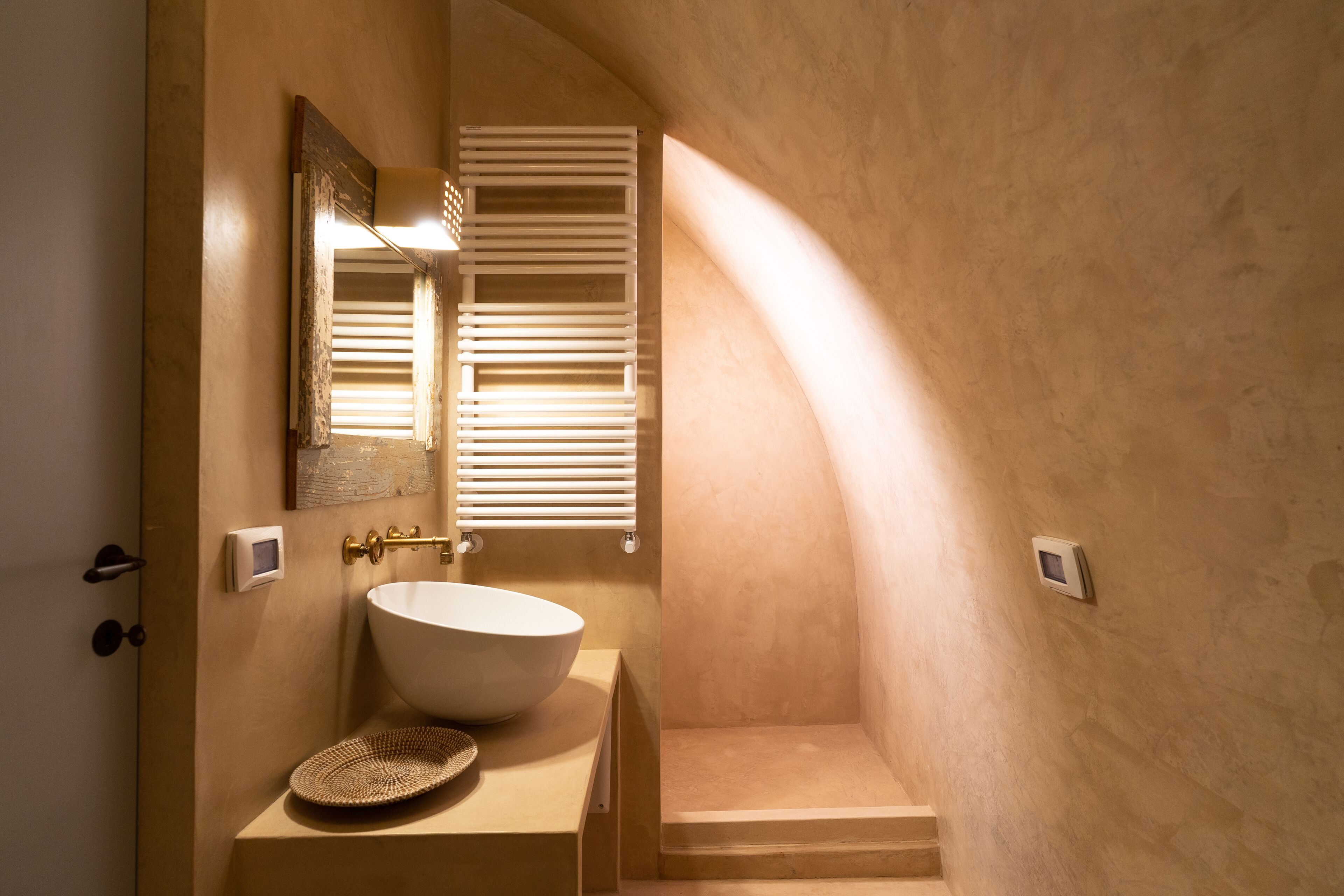 Un baño con un lavamanos grande blanco, un espejo y una ventana con persianas.