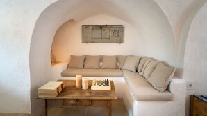Una habitación acogedora con un sofá curvo, una mesa de madera con un tablero de ajedrez y un estante rústico montado en la pared.