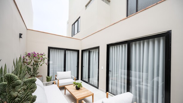 A modern outdoor living area with a sofa, a table, and potted plants.
