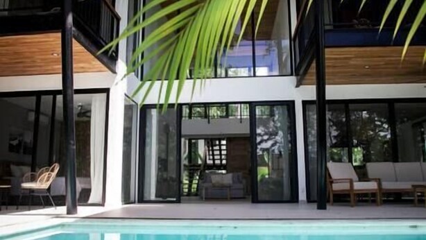 Ein modernes Haus mit Pool, großen Fenstern und Sitzgelegenheit im Freien.