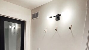 A hallway with a bench, a basket, and a wall-mounted light fixture.