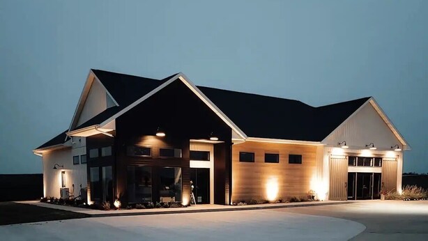 A modern two-story house with a large driveway and a covered outdoor area.
