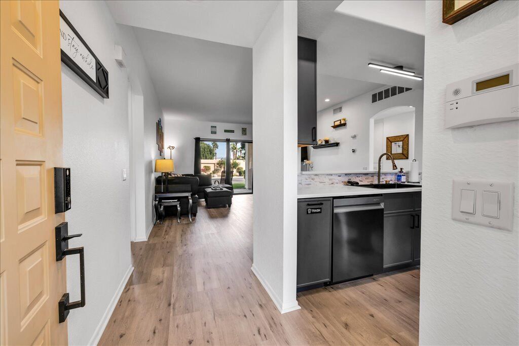A modern kitchen with a dishwasher, a dining area with a table and chairs, and a view of the outdoors.
