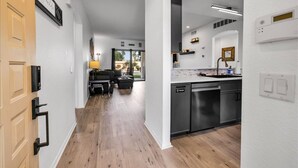 A modern kitchen with a dishwasher, a dining area with a table and chairs, and a view of the outdoors.