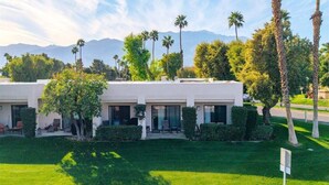 A modern two-story building with a flat roof, large windows, and a well-maintained lawn.