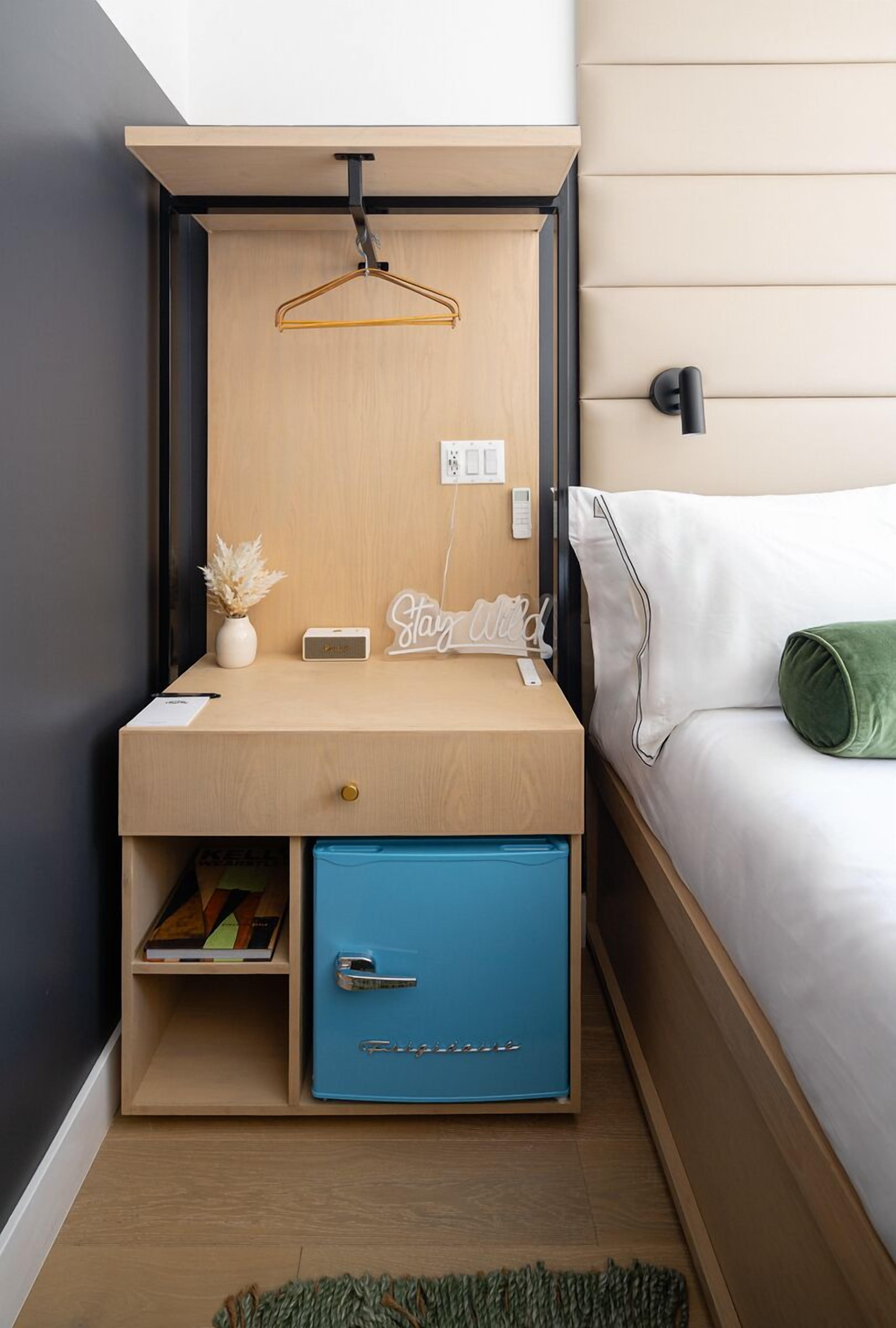 A compact bedroom with a built-in desk, a small wardrobe, and a bed with a green pillow.