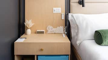 A compact bedroom with a built-in desk, a small wardrobe, and a bed with a green pillow.