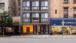Un edificio de varios pisos con fachada moderna, amplias ventanas y entrada a nivel de calle con un letrero.