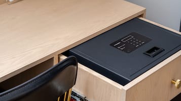Un escritorio de madera con un cajón negro, un mueble rojo y una silla negra.