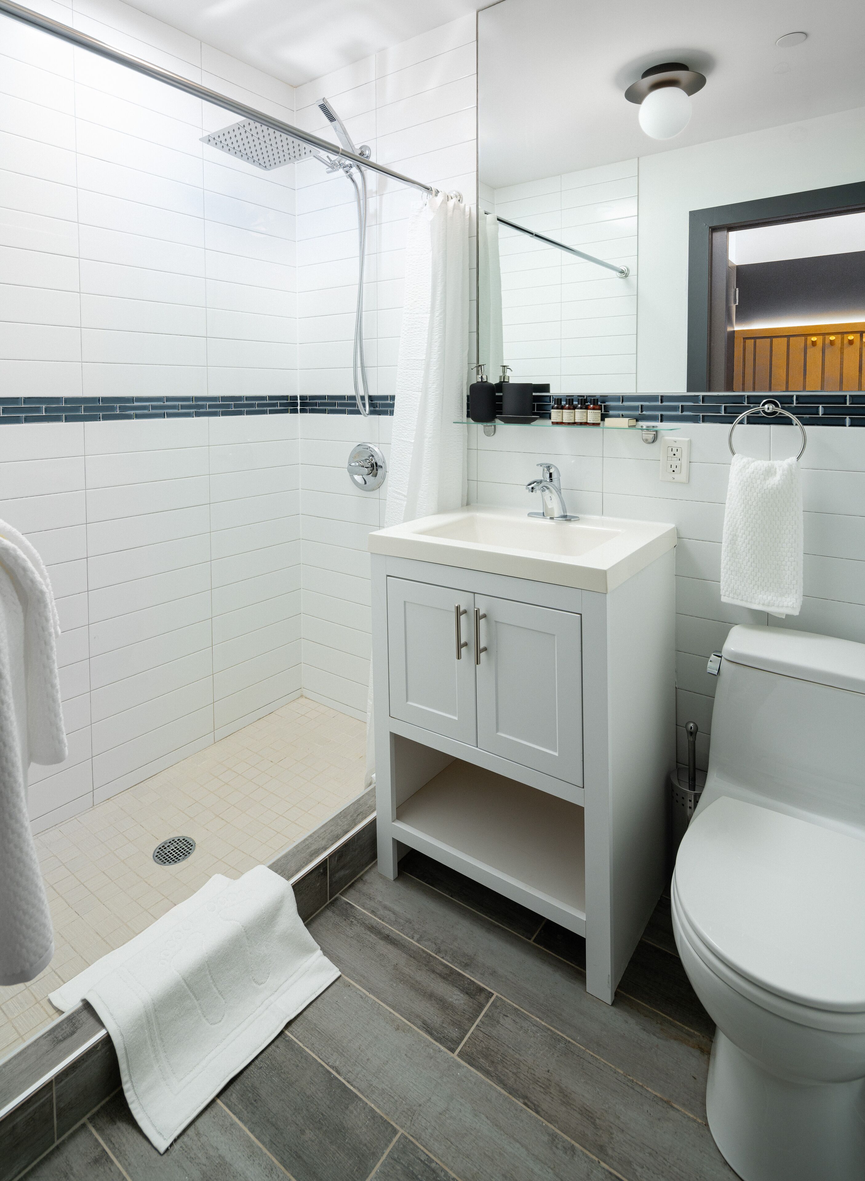 Een moderne badkamer met douche, toilet en wastafel.