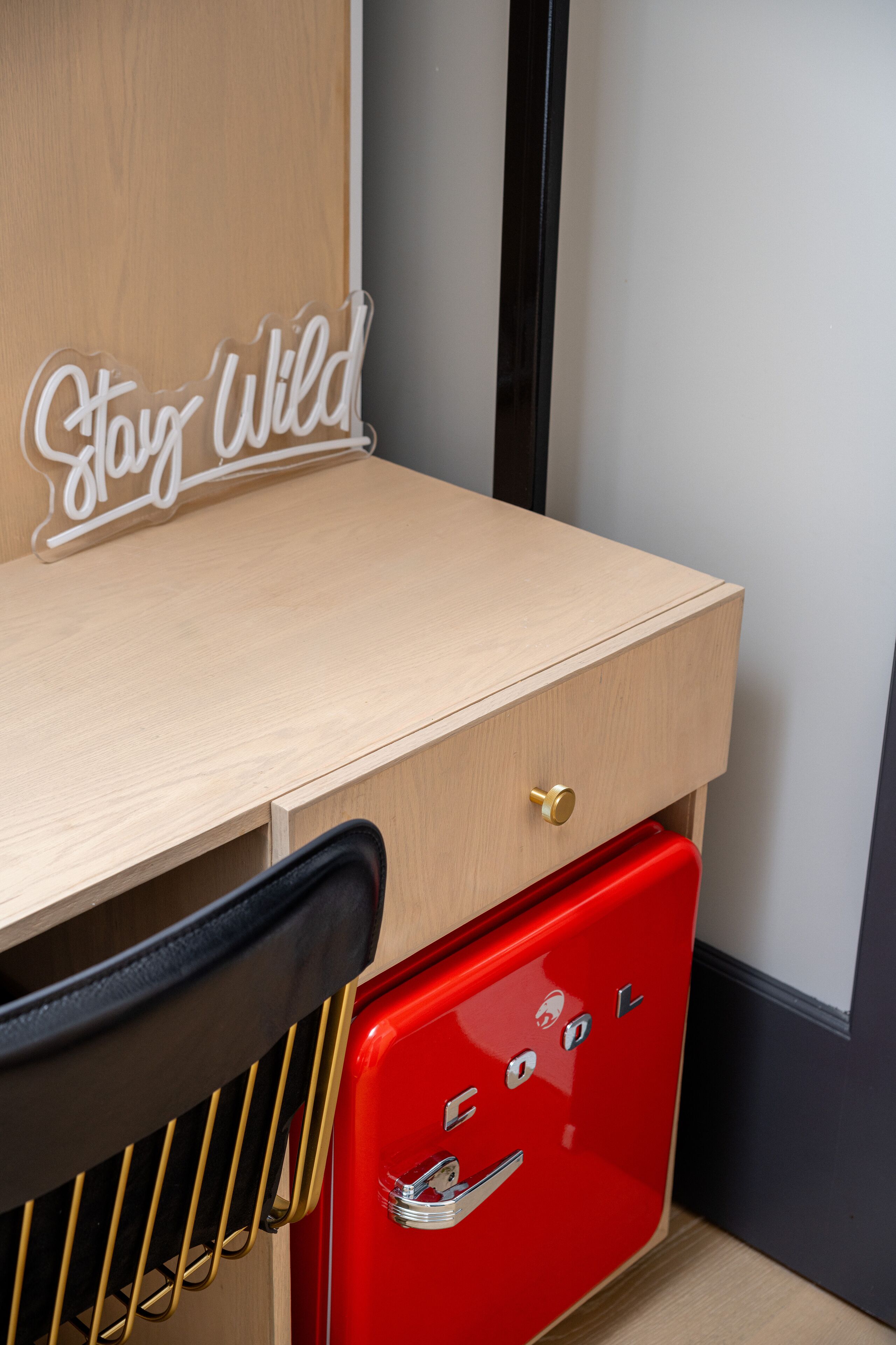 A wooden desk with a drawer and a red vintage-style refrigerator.