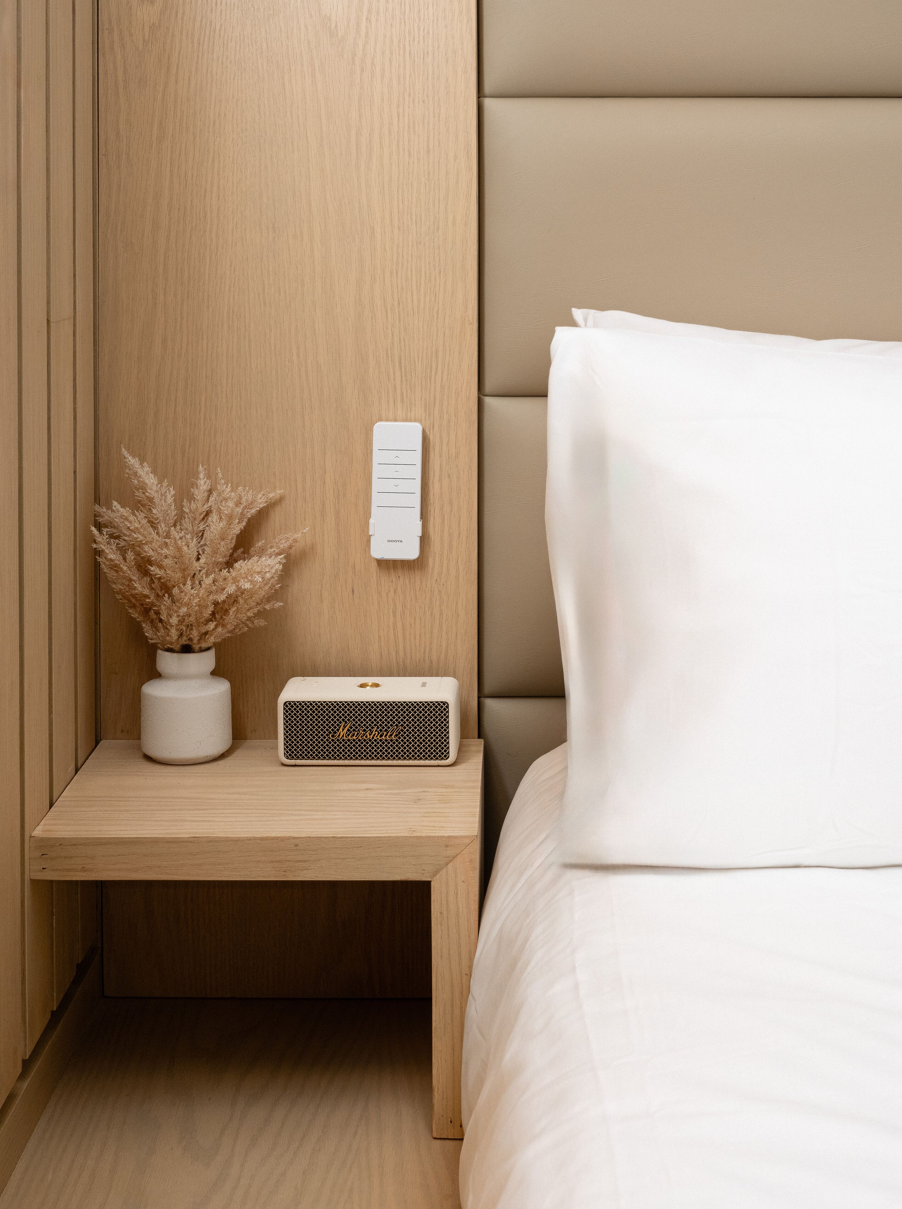 A neatly arranged bedside table with a white lamp, a small potted plant, and a Marshall speaker.