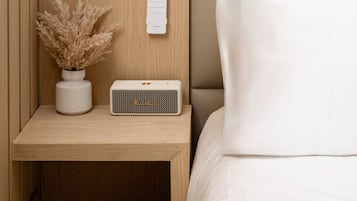 A neatly arranged bedside table with a white lamp, a small potted plant, and a Marshall speaker.
