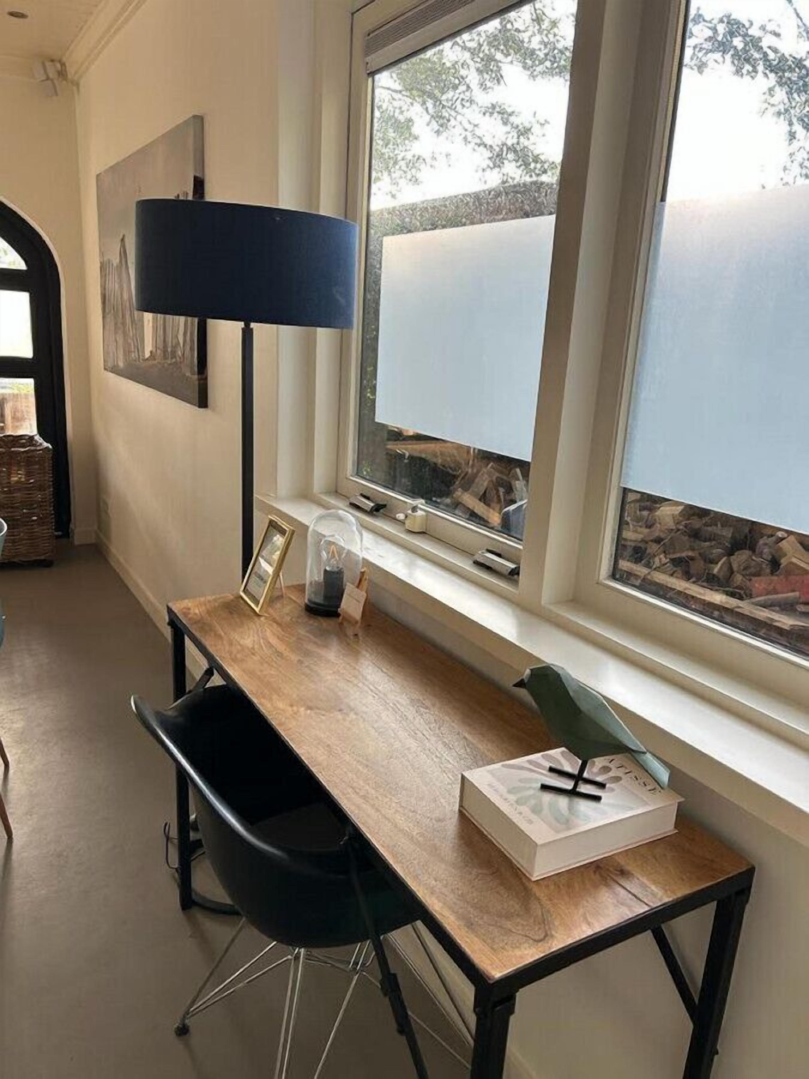 A modern room with a wooden desk, black chair, and a large window with a view of trees.