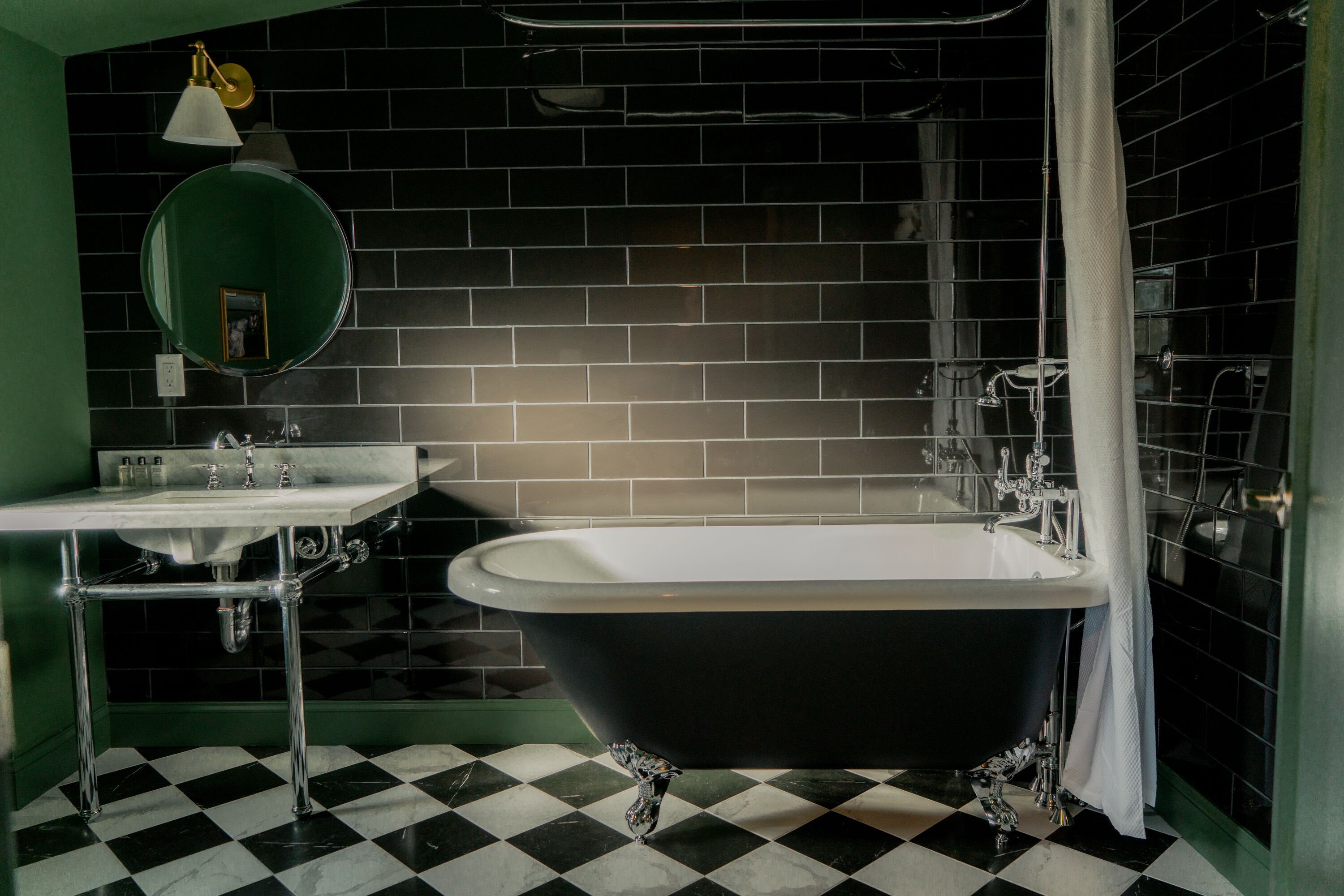 A bathroom with a black bathtub, a sink, a mirror, and a checkered floor.