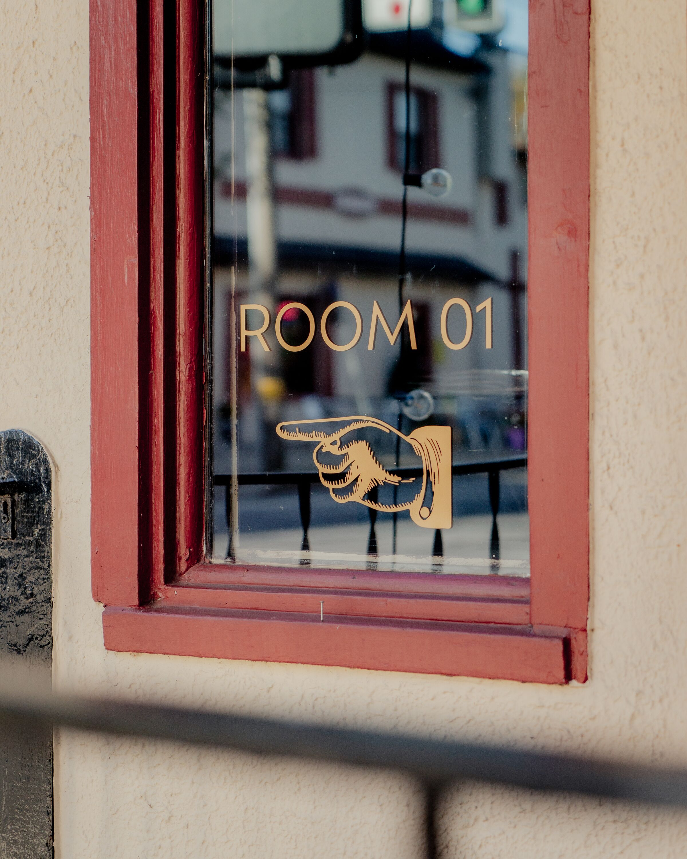 A window with a sign reading "ROOM 01" and a hand pointing icon.
