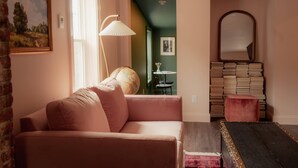 Un salon chaleureux avec un canapé rose, un globe terrestre et une pile de livres.