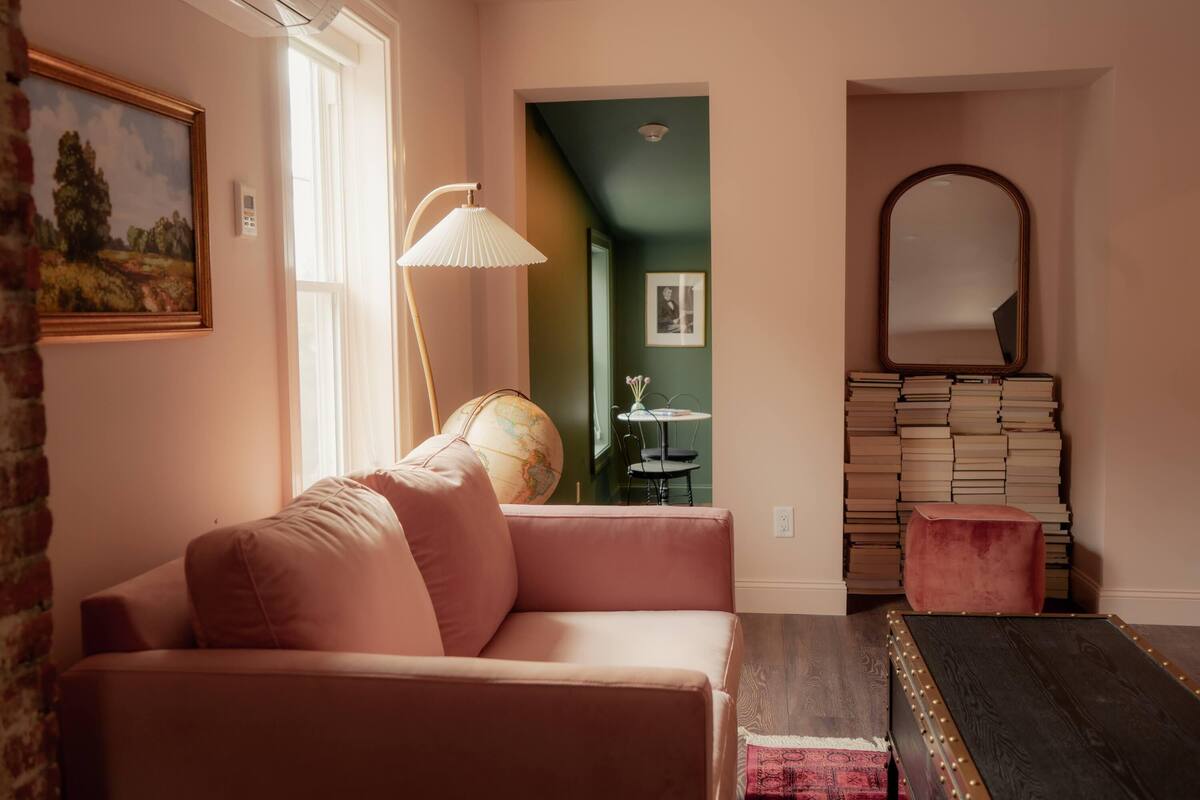 A cozy living room with a pink sofa, a globe, and a stack of books.
