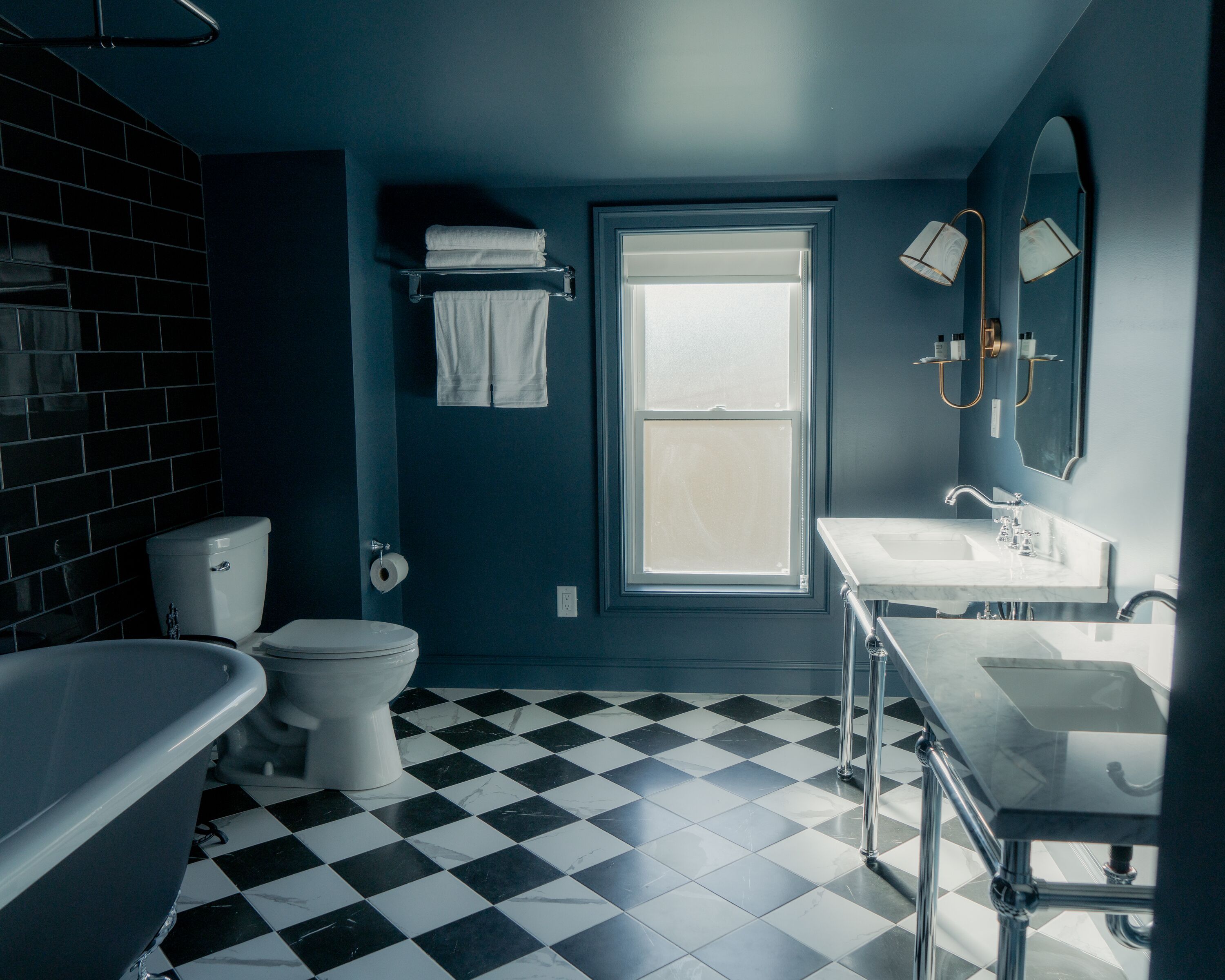 A bathroom with a checkered floor, a toilet, a bathtub, and a sink with a mirror.
