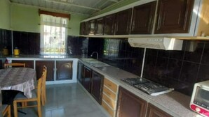 Cocina compacta con comedor, que incluye armarios oscuros, una estufa a gas y un microondas.