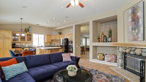 A spacious living room with a blue sofa, a coffee table, and a fireplace. - Large 5 Bedroom Home - Family Getaway w/ Pool (Turlock)