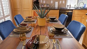 A wooden dining table set with plates, bowls, glasses, and cutlery. - Large 5 Bedroom Home - Family Getaway w/ Pool (Turlock)