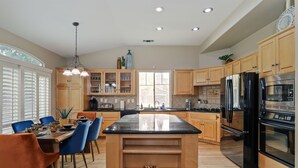 A spacious kitchen with wooden cabinets, a central island, and modern appliances. - Large 5 Bedroom Home - Family Getaway w/ Pool (Turlock)