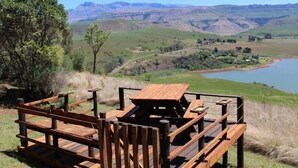 A wooden deck with a picnic table overlooking a scenic valley with mountains in the background.