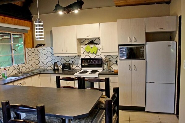 Una cocina con armarios blancos, estufa, microondas y refrigerador.