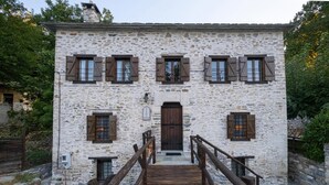 Un bâtiment en pierre avec un escalier en bois menant à une porte.