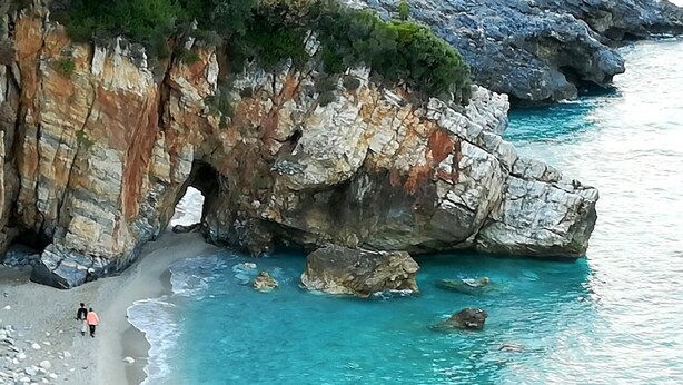 Un paysage côtier avec une falaise rocheuse et une mer turquoise aux eaux limpides.