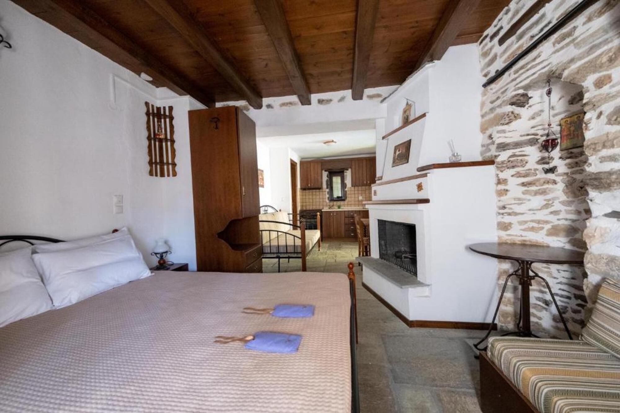 Un dormitorio con cama, mesita de noche, una pequeña mesa y pared de piedra.