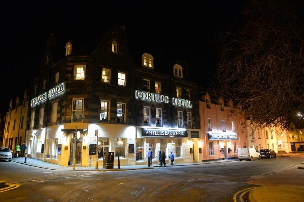 A historic building with a sign for 'Portree Hotel' and 'Antlers Bar & Grill'.