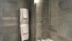 Ein modernes Badezimmer mit einer gläsernen Duschkabine, einer Badewanne und einem Handtuchhalter mit zwei weißen Handtüchern.
